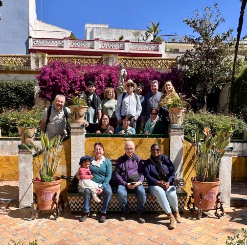 Front Row, seated (L-R): [Daughter of Mathias Chamaillard]; Nesrin Ozoren, 2002-2005, Turkey; Lech Czerski, 2002-2005, Poland; [Wife of Mathias Chamaillard] Middle Row, seated (L-R): [Wife of Hideki Hara]; [Daughter of Hideki Hara]; Ruth Álvarez, 2002-2004, Spain Back Row, standing (L-R): Mathias Chamaillard, 2003-2005, France; [Son of Hideki Hara]; [Wife of Ramon Merino]; Dr. Nunez (in hat); Hideki Hara, 2013-2019, Japan; Ramon Merino, 1993-1995, Spain; Angela Bernabéu, 2003, Spain